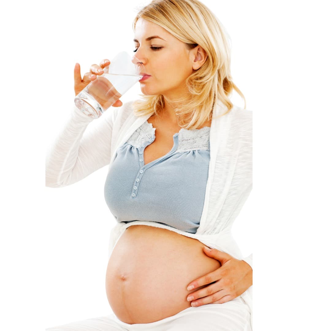 Pregnant woman drinking a glass of water with one hand resting on her belly