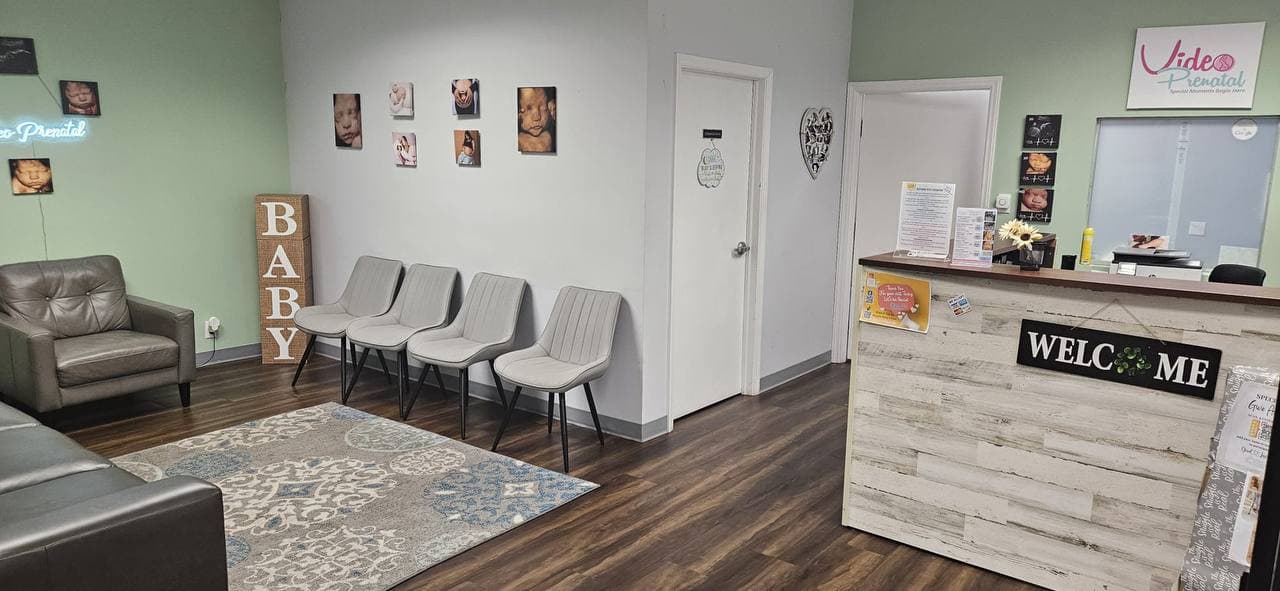Video Prenatal waiting room and welcome desk in Charlotte with armchairs, a row of chairs and ultrasound photos on the walls